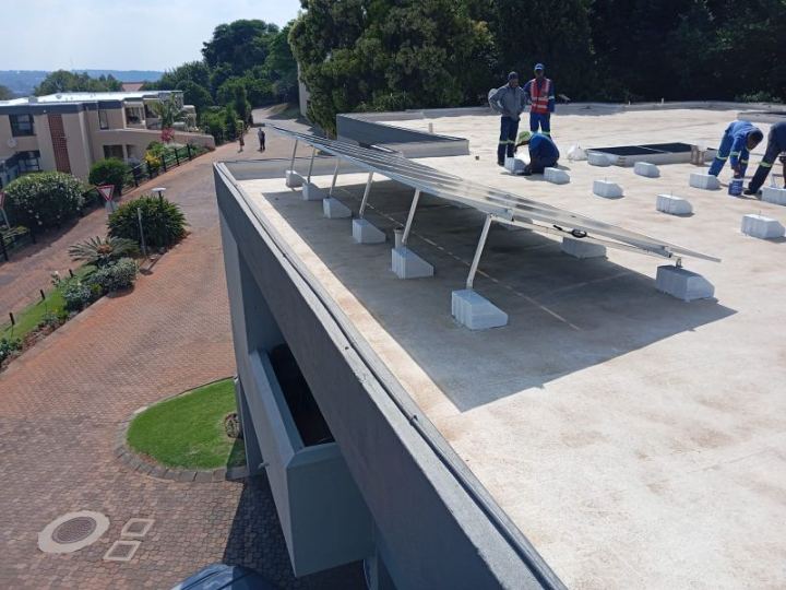 Installers mounting solar panels on a flat roof at a retirement village